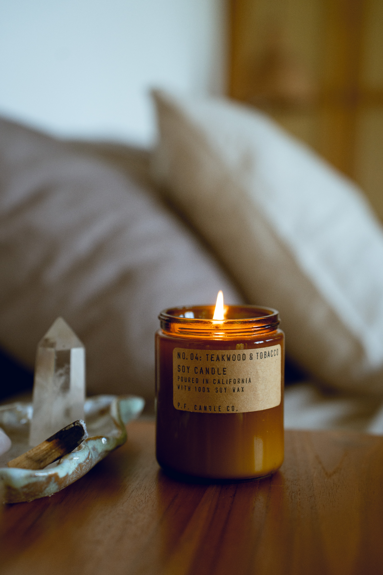A softly glowing candle beside a clear quartz crystal in a calm home setting